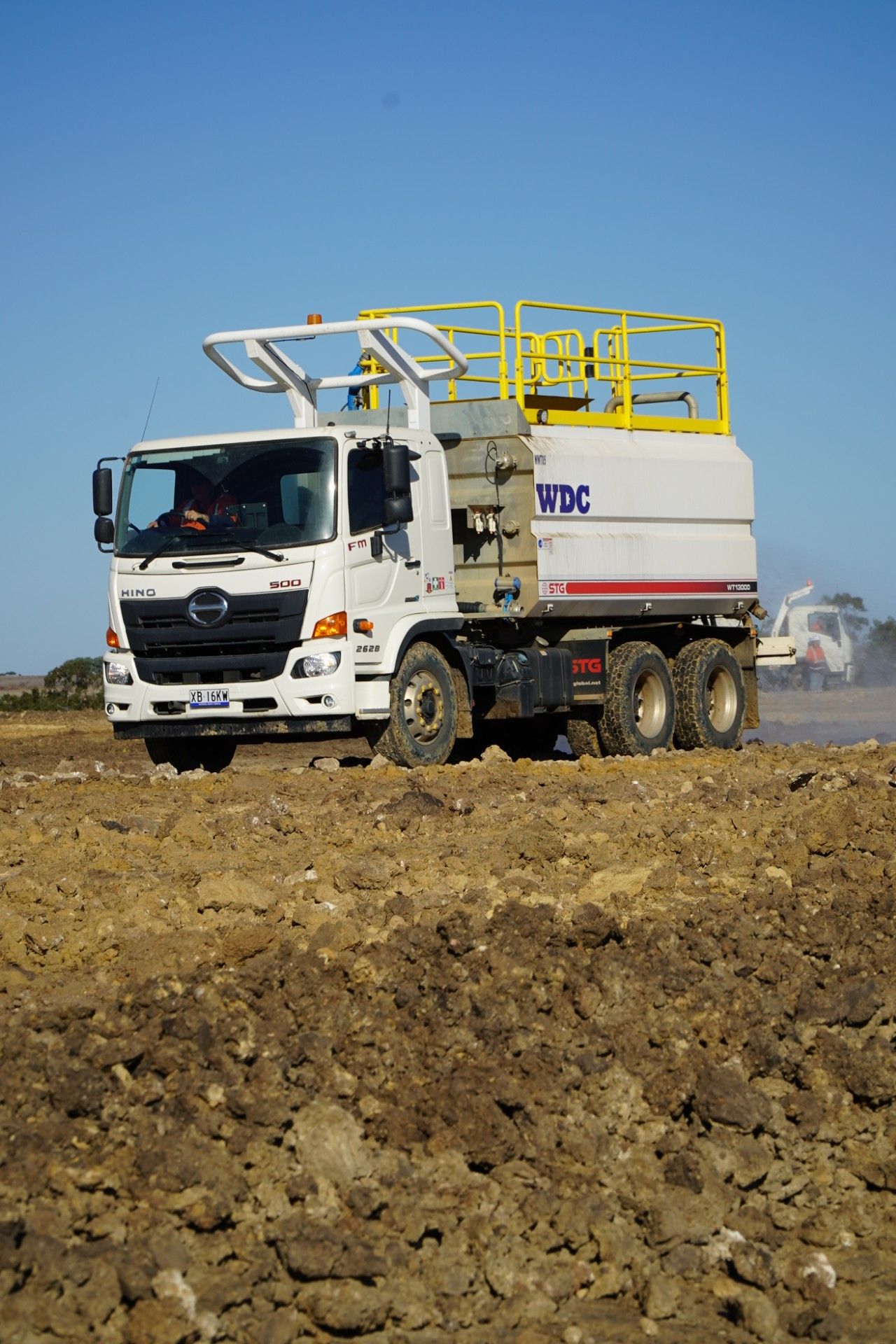 White utility truck on a rocky field under a clear blue sky