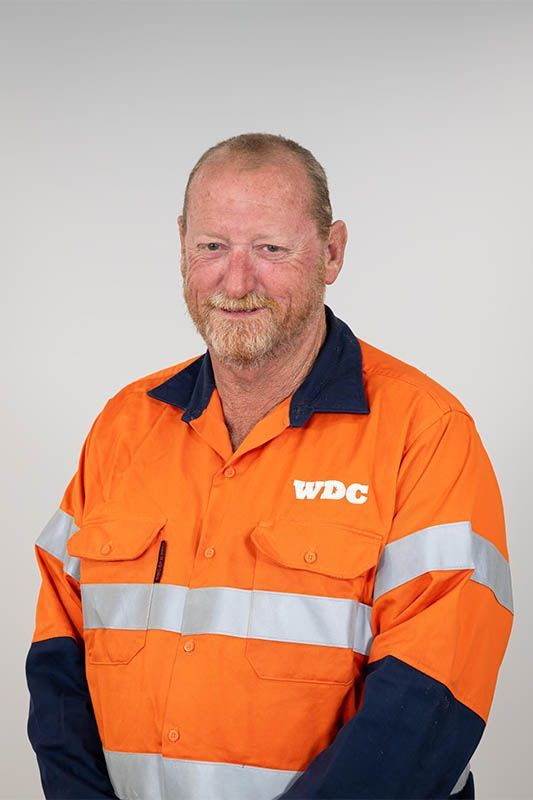 Worker in orange WDC high-visibility jacket, standing against a plain background.