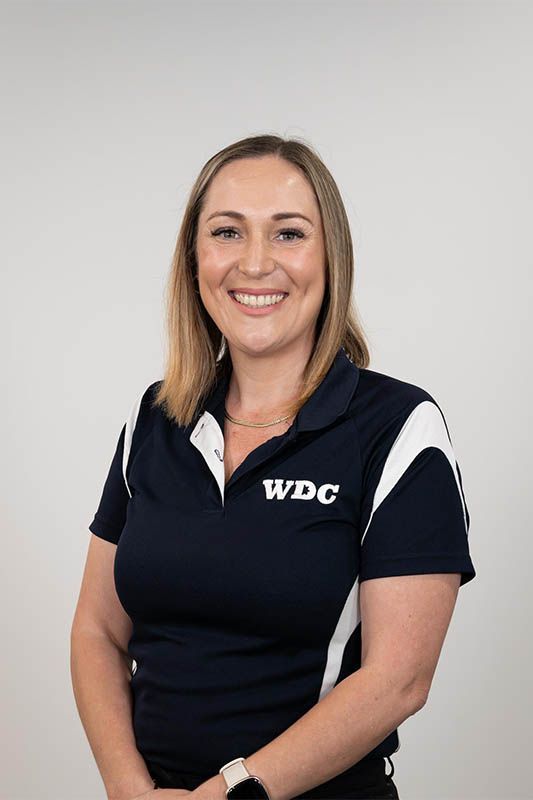 Woman in a navy WDC polo shirt smiling against a light gray background