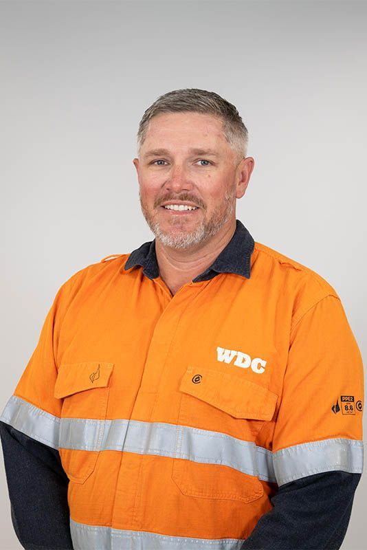 Portrait of a smiling worker in an orange high-visibility jacket with reflective stripes and a WDC logo