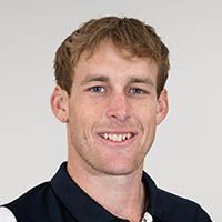 Portrait of a smiling man in a dark collared shirt against a light background
