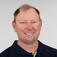 Smiling man in a dark polo shirt against a light gray background