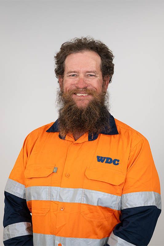 Smiling worker in orange high-visibility jacket with reflective stripes and dark sleeves, standing against a plain background