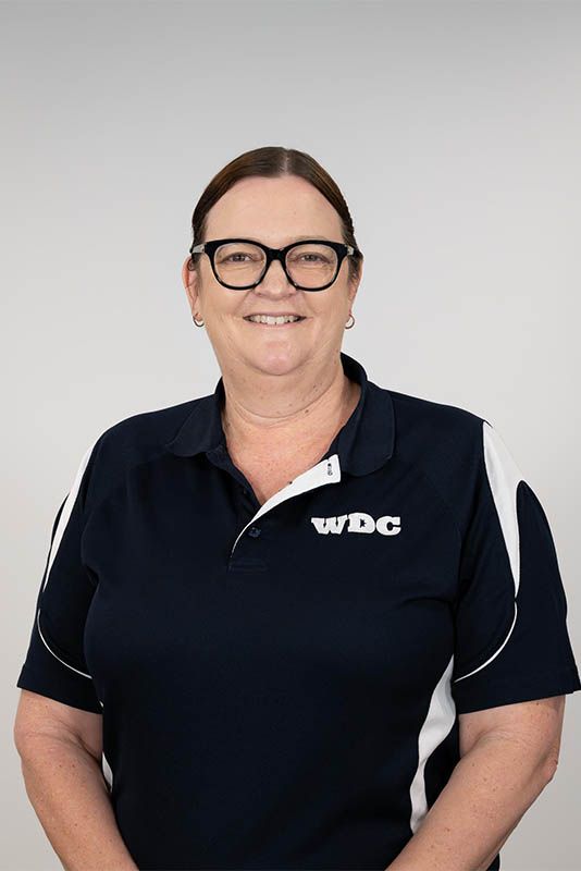 Smiling person in a navy WDC polo shirt against a light gray background
