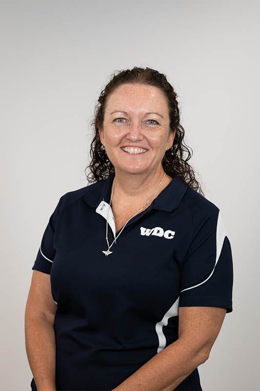 Smiling woman in a navy polo shirt against a plain light background