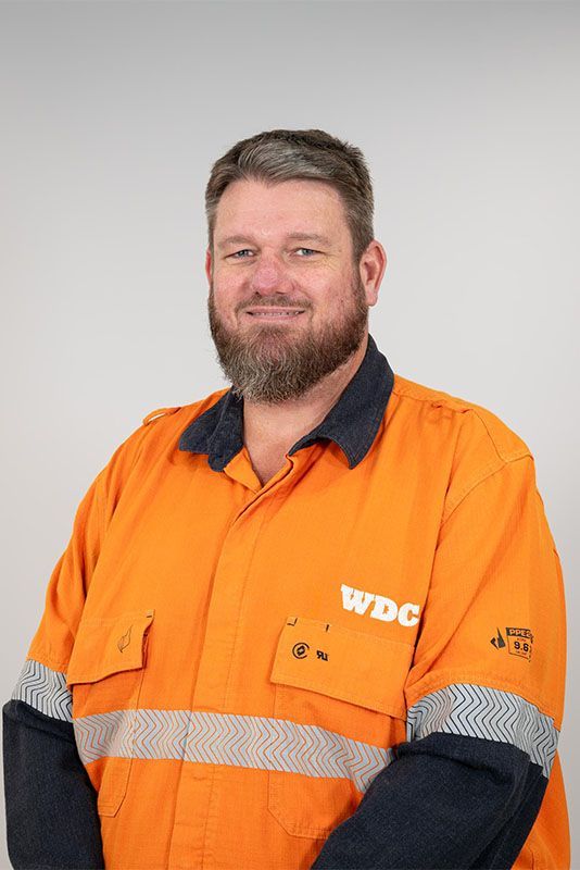 Smiling worker in orange high-visibility jacket with reflective stripes and navy sleeves against a gray background