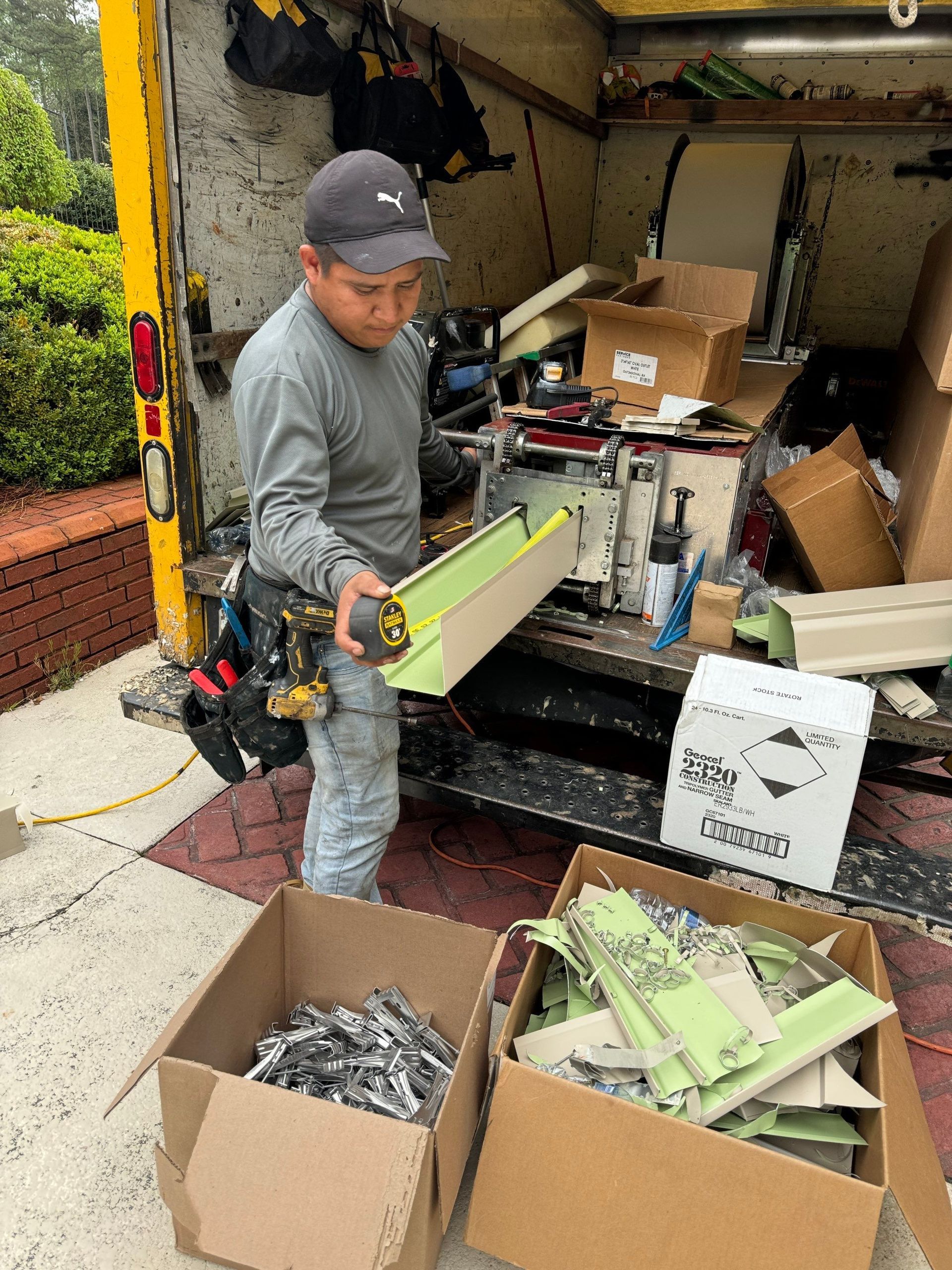 Man loading green metal parts from a truck into boxes on the sidewalk