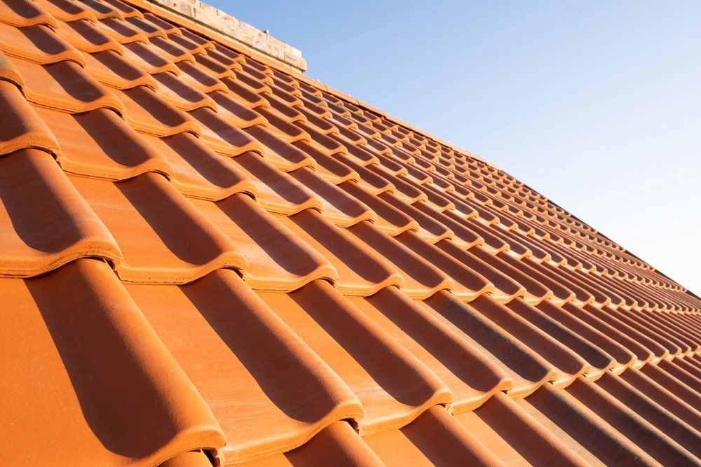 Overlapping rows of yellow ceramic roofing tiles — Roof Repointing in Bonogin QLD