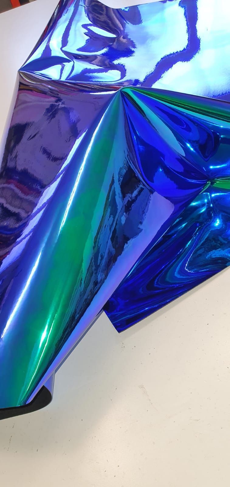 Un pezzo di carta stagnola blu e verde è appoggiato su un tavolo.