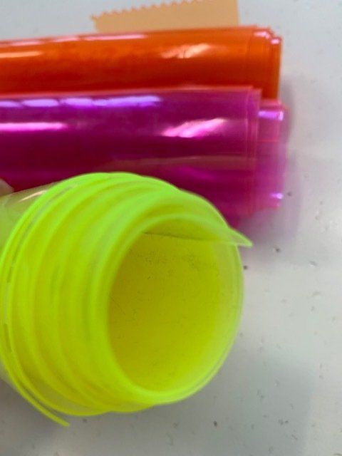 Primo piano di un tubo di plastica giallo e rosa su un tavolo.