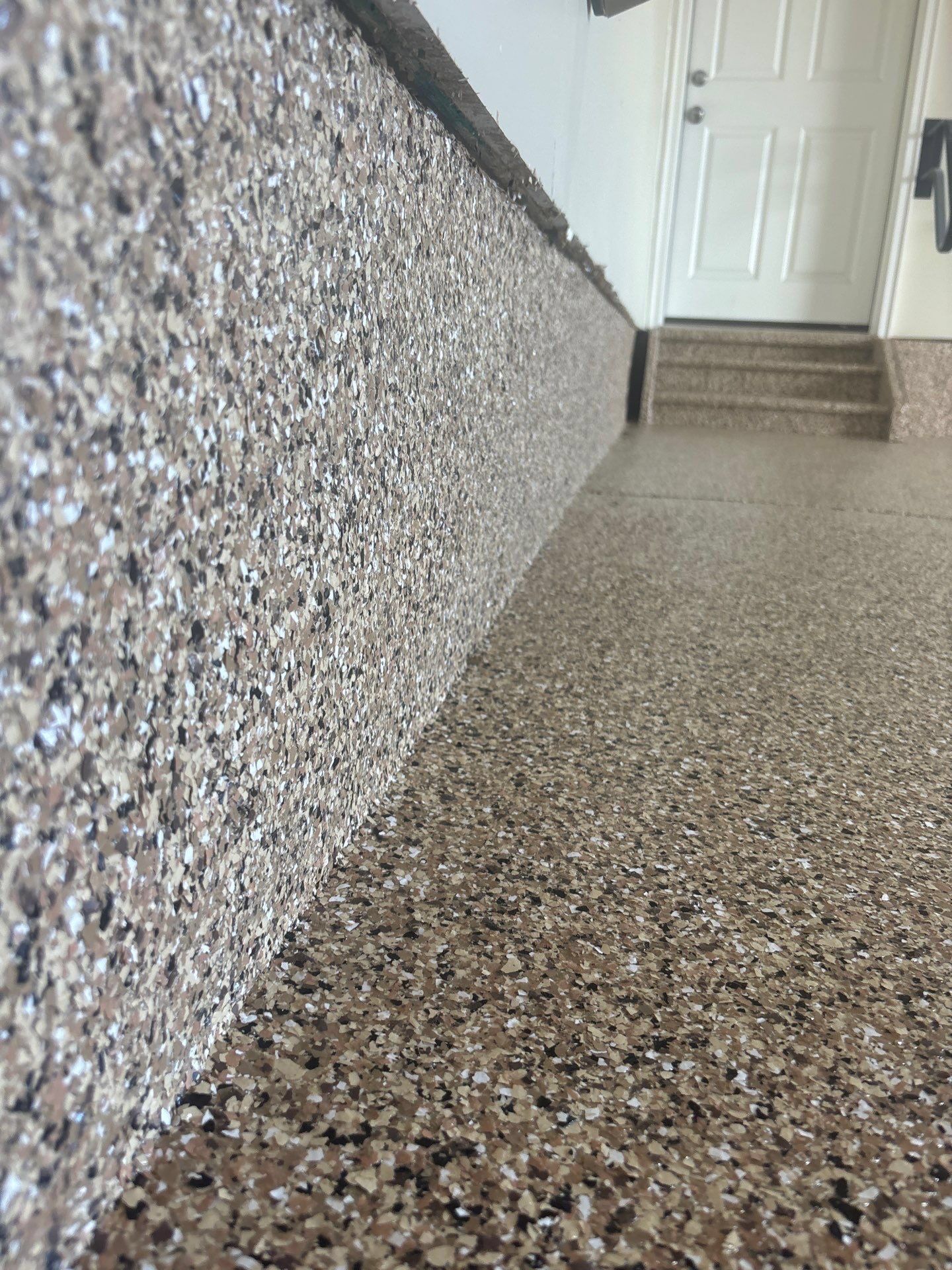 Terrazzo hallway floor and wall leading to a white door and short steps