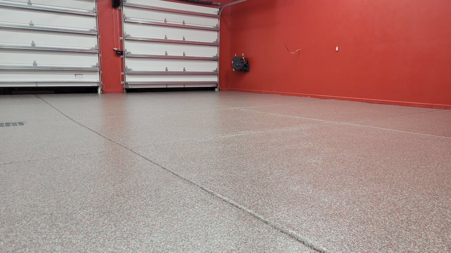 Empty concrete floor beside red wall and gray metal shutter door