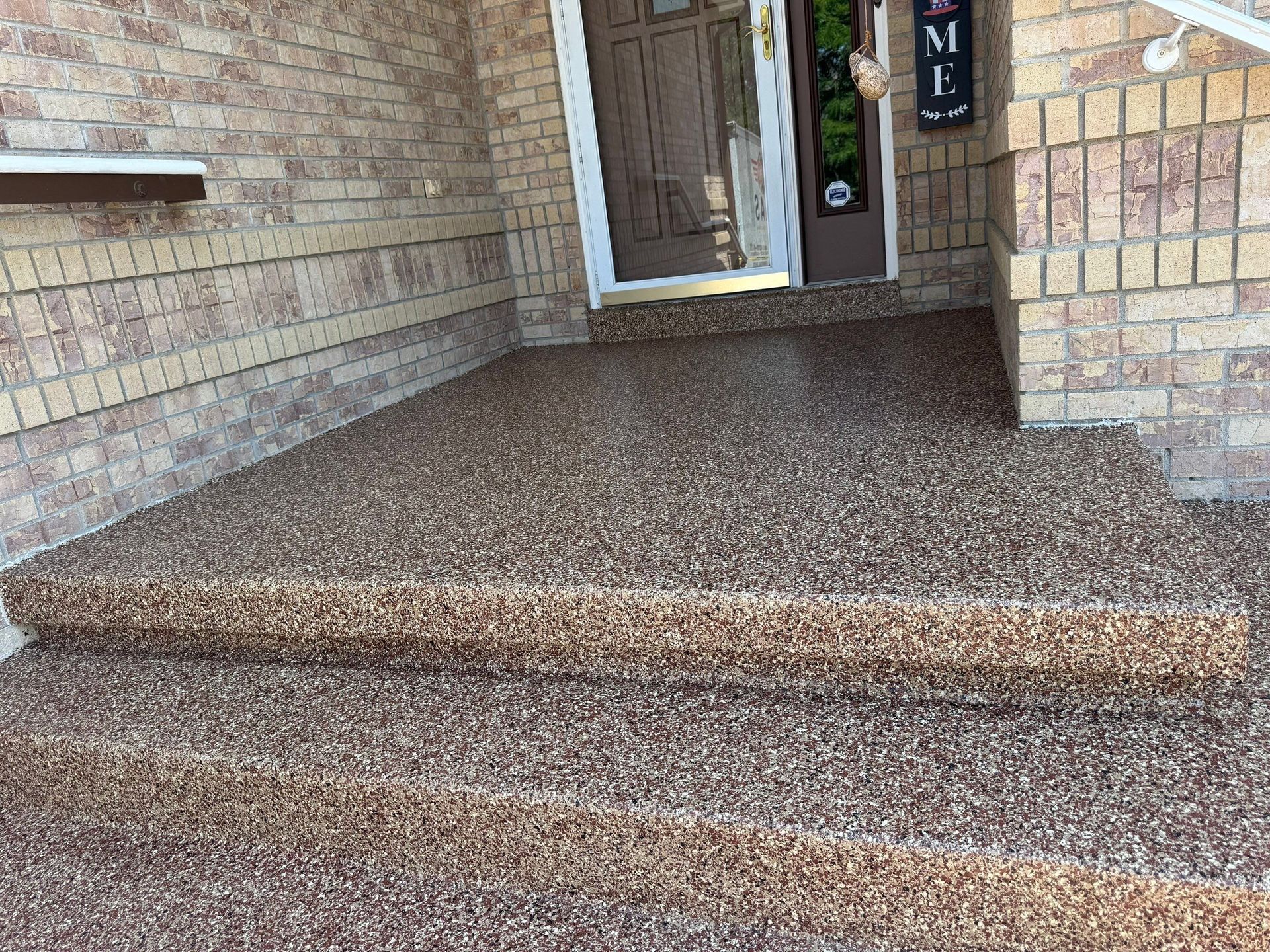 Brick front porch with carpeted steps leading to a glass-paneled entrance door