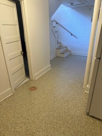 Narrow hallway with white doors, speckled carpet, and stairs ahead with a handrail.