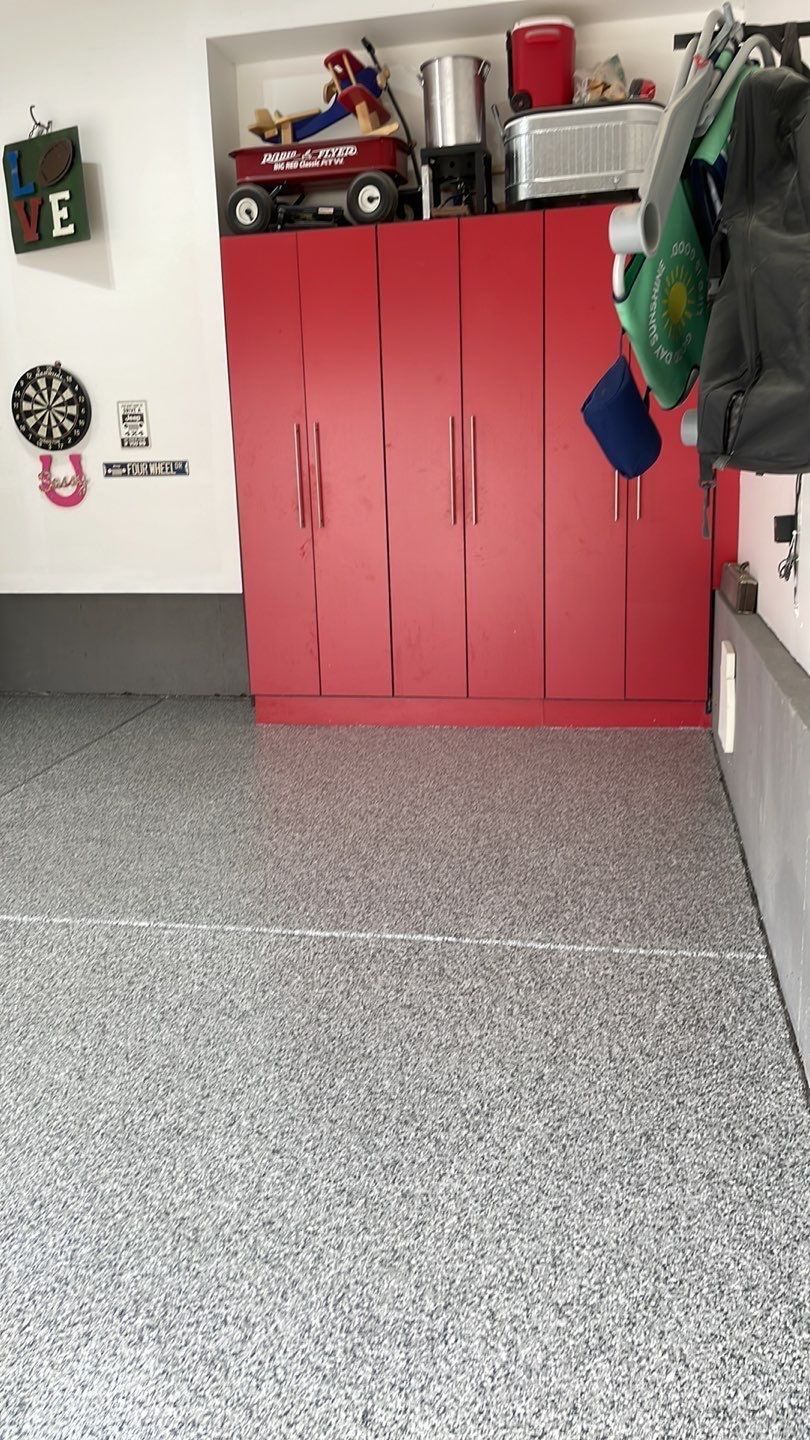 Red storage cabinets in a garage with tools and hanging items on the walls.
