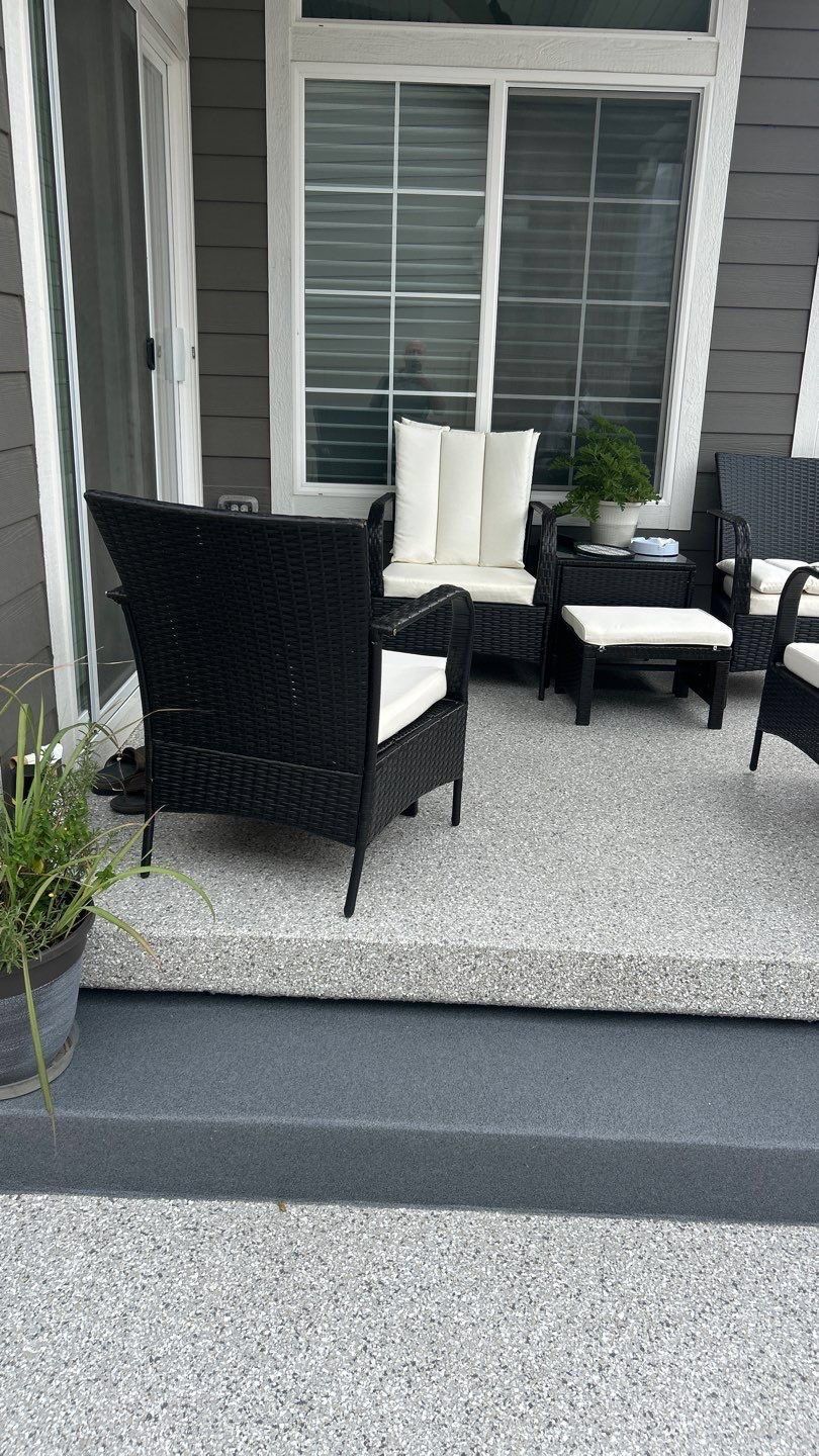 Patio seating with black and white chairs on a gray porch in front of windows