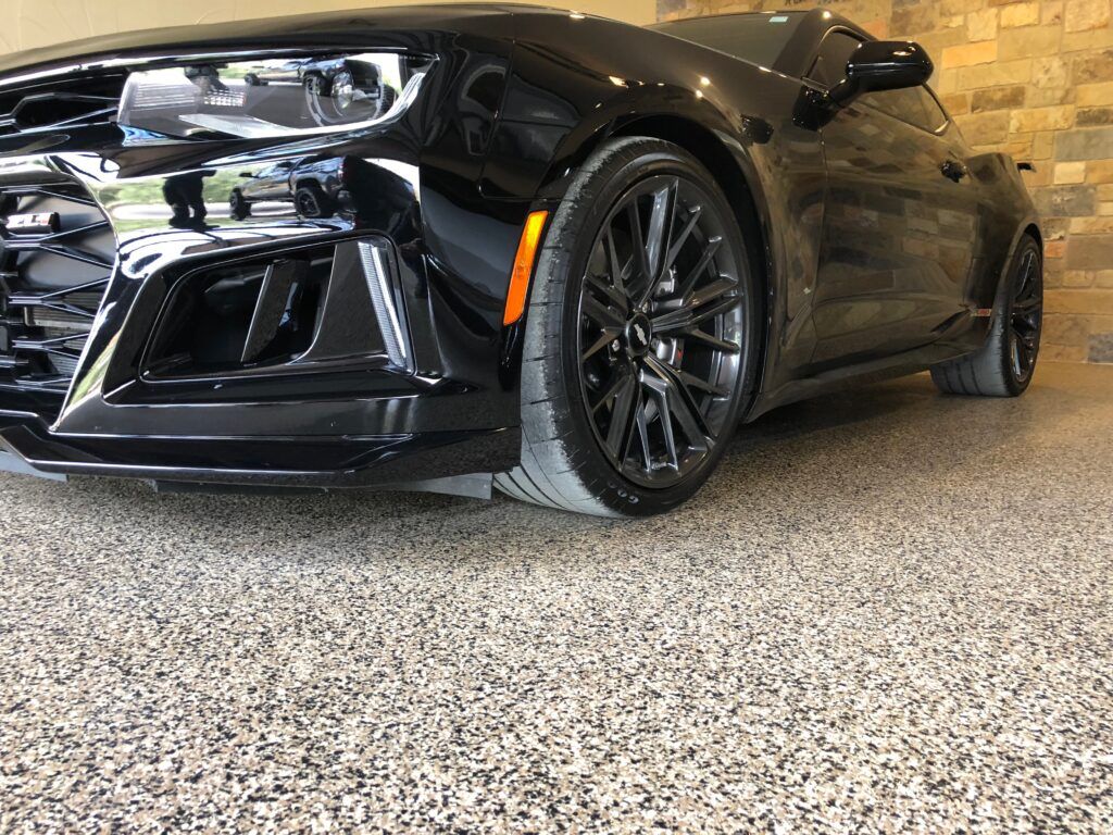 Black sports coupe parked indoors, showing front-left side and glossy black rims.
