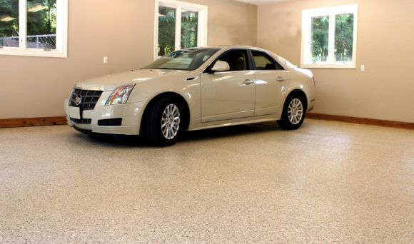 Silver sedan parked in a clean beige garage with windows and a speckled floor