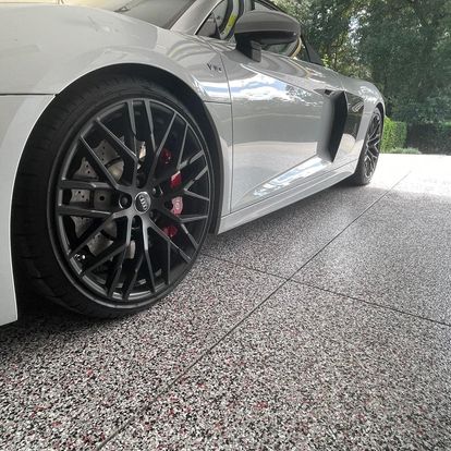 White sports car with black rims and red brake calipers parked on a tiled driveway