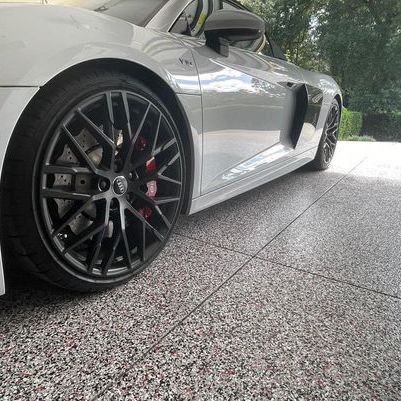 Silver sports car with black wheels parked on a tiled driveway outdoors