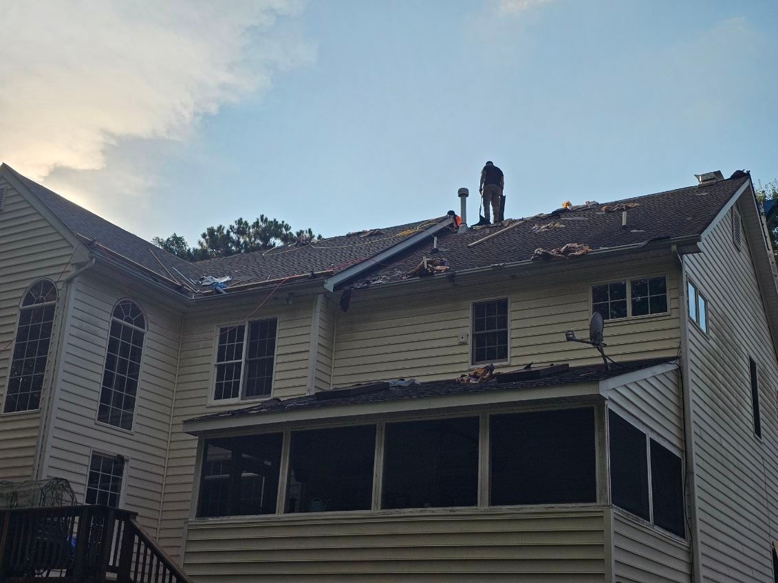 A two-story residential home with visible roof damage and deterioration along the roofline and shingles requiring repair by D