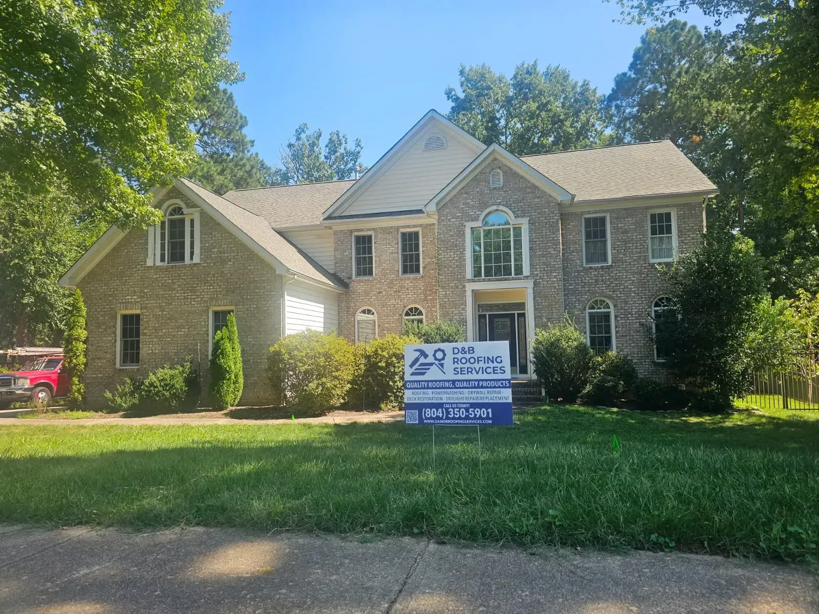 A two-story brick residential home with multiple roof sections and dormers visible from the front exterior by D & B Services
