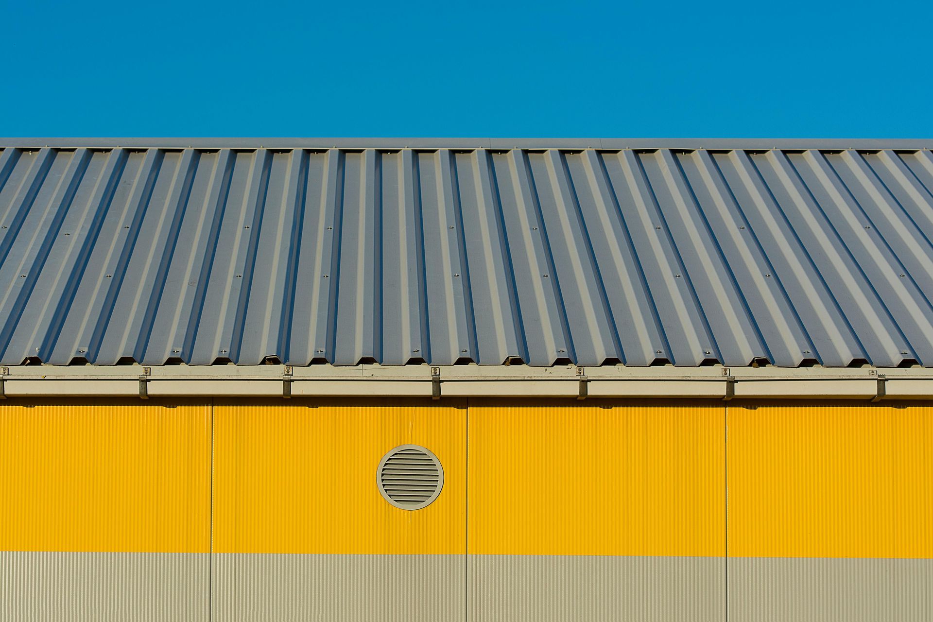 Metal roof with gable vent providing essential attic air ventilation to extend roof lifespan