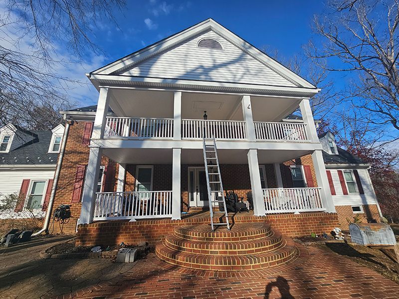A large white house with a large porch and stairs.