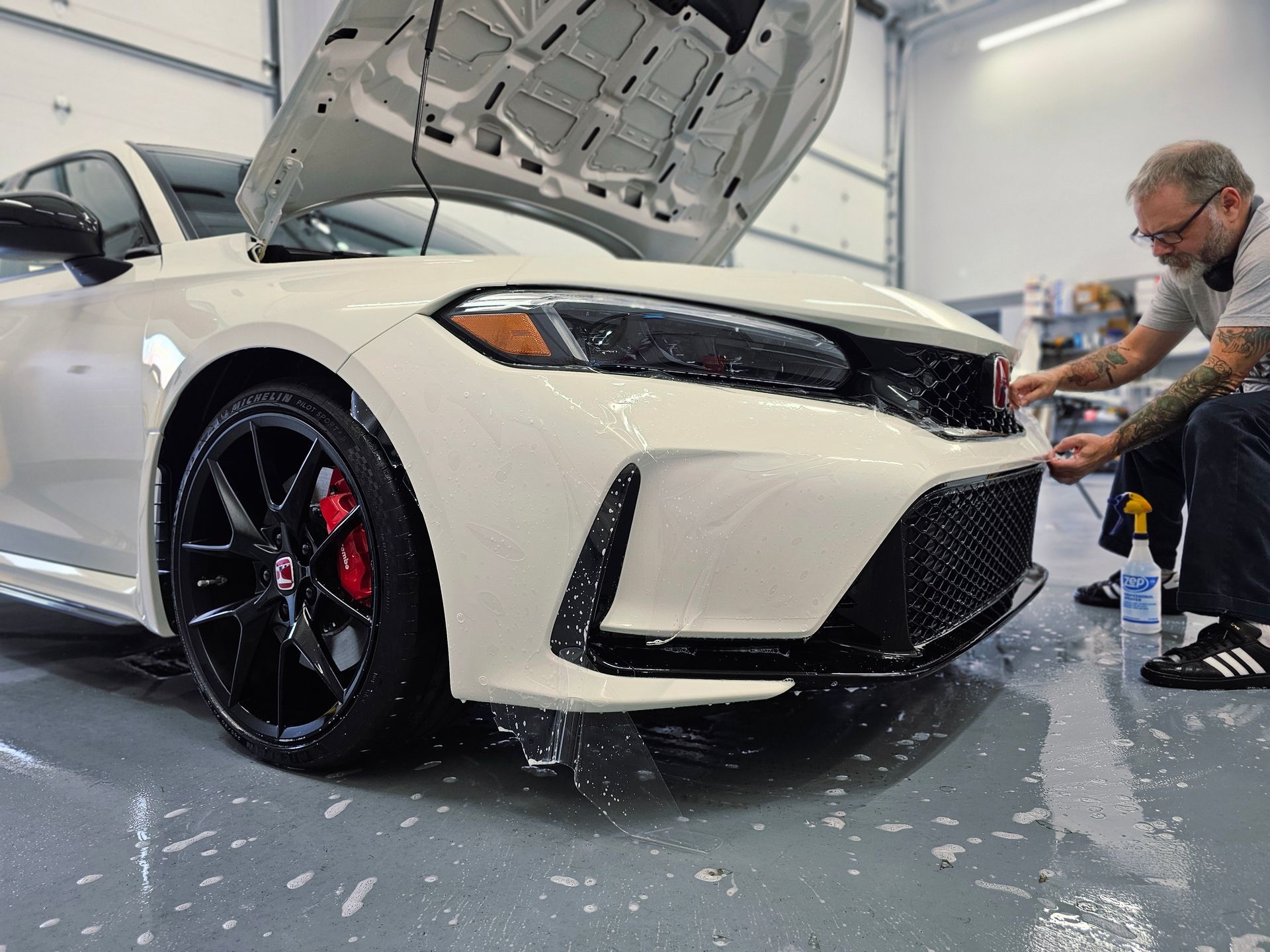 Person polishing a black truck door with a buffer in an auto detailing shop