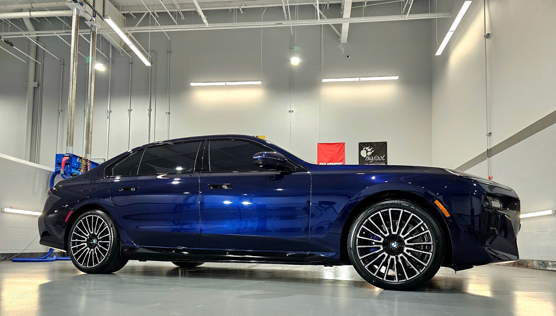 A dark blue Dodge Charger parked in a bright, clean indoor garage with overhead lighting.
