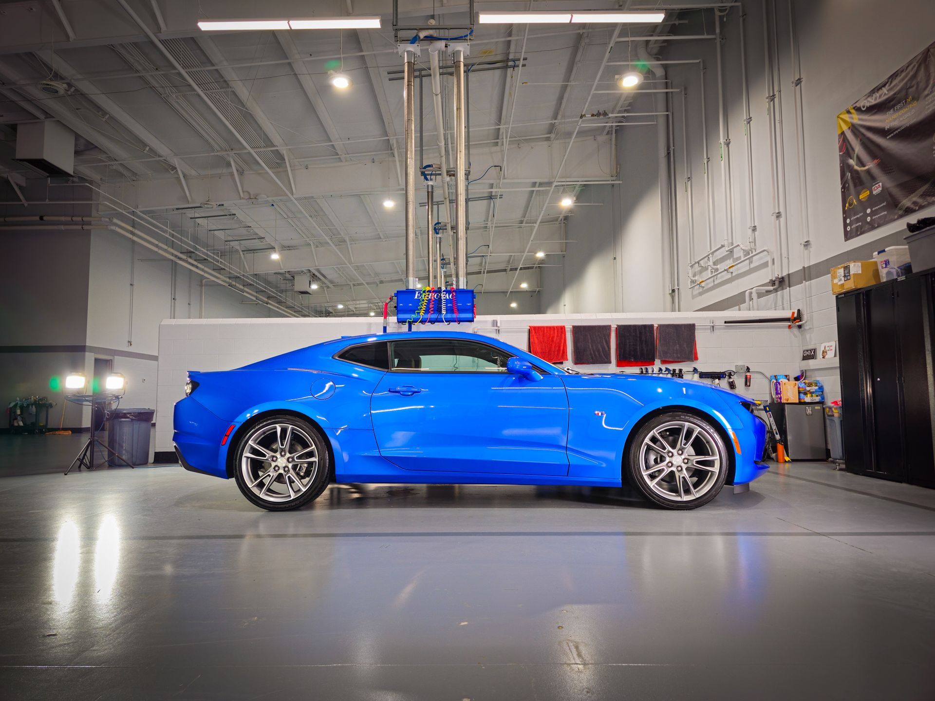 Bright blue sports car in an industrial garage under bright lights