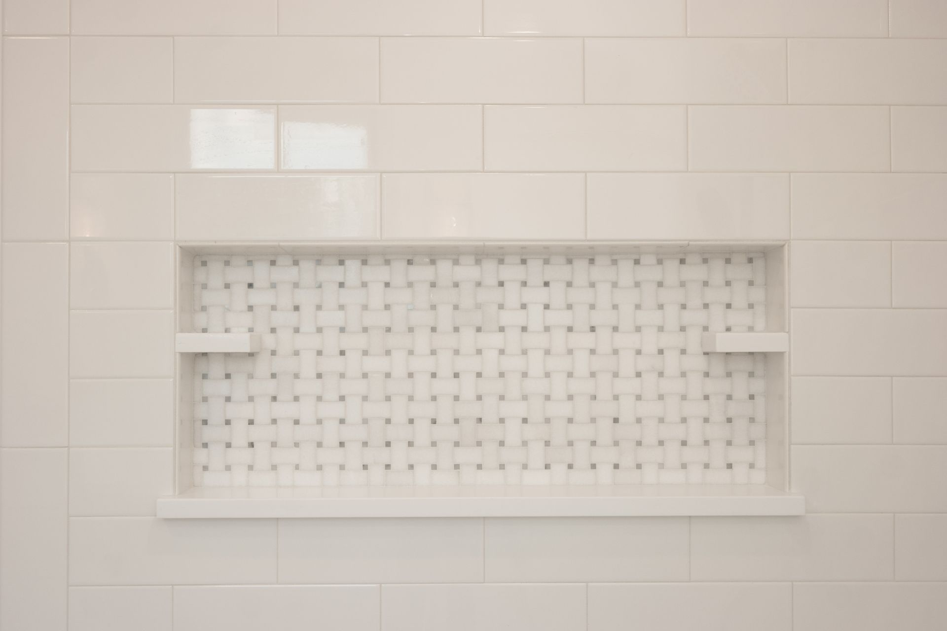 White rectangular shower niche with a decorative basket-weave tile back, white border, and small side shelves.