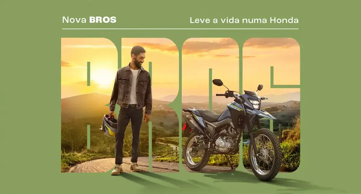 Homem com uma motocicleta em uma estrada de montanha, em tons de verde e dourado. Propaganda da Honda Bros.
