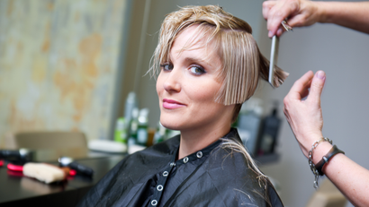 A woman is getting her hair cut at a salon.