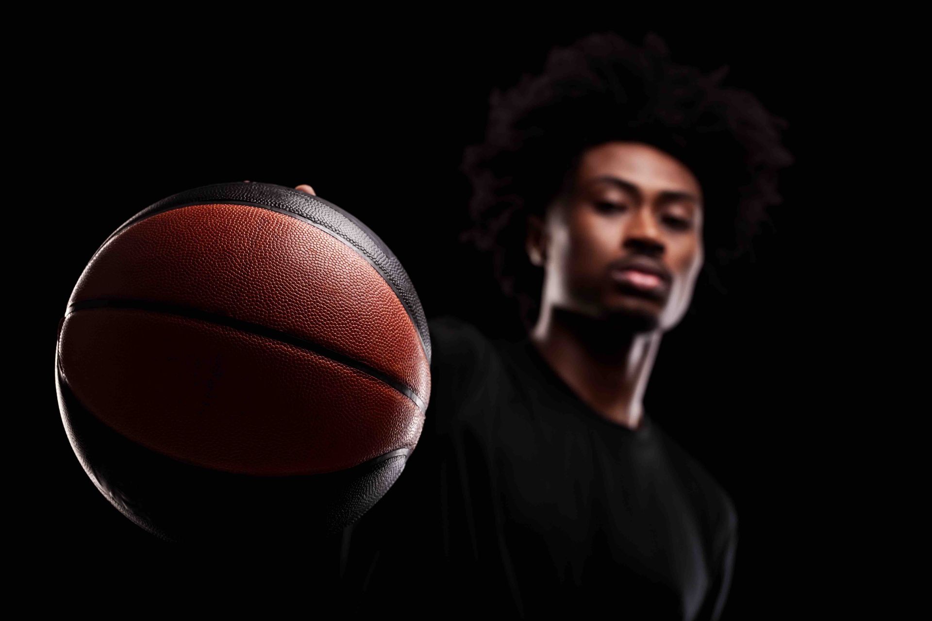 A man in a black shirt is holding a basketball in his hand.