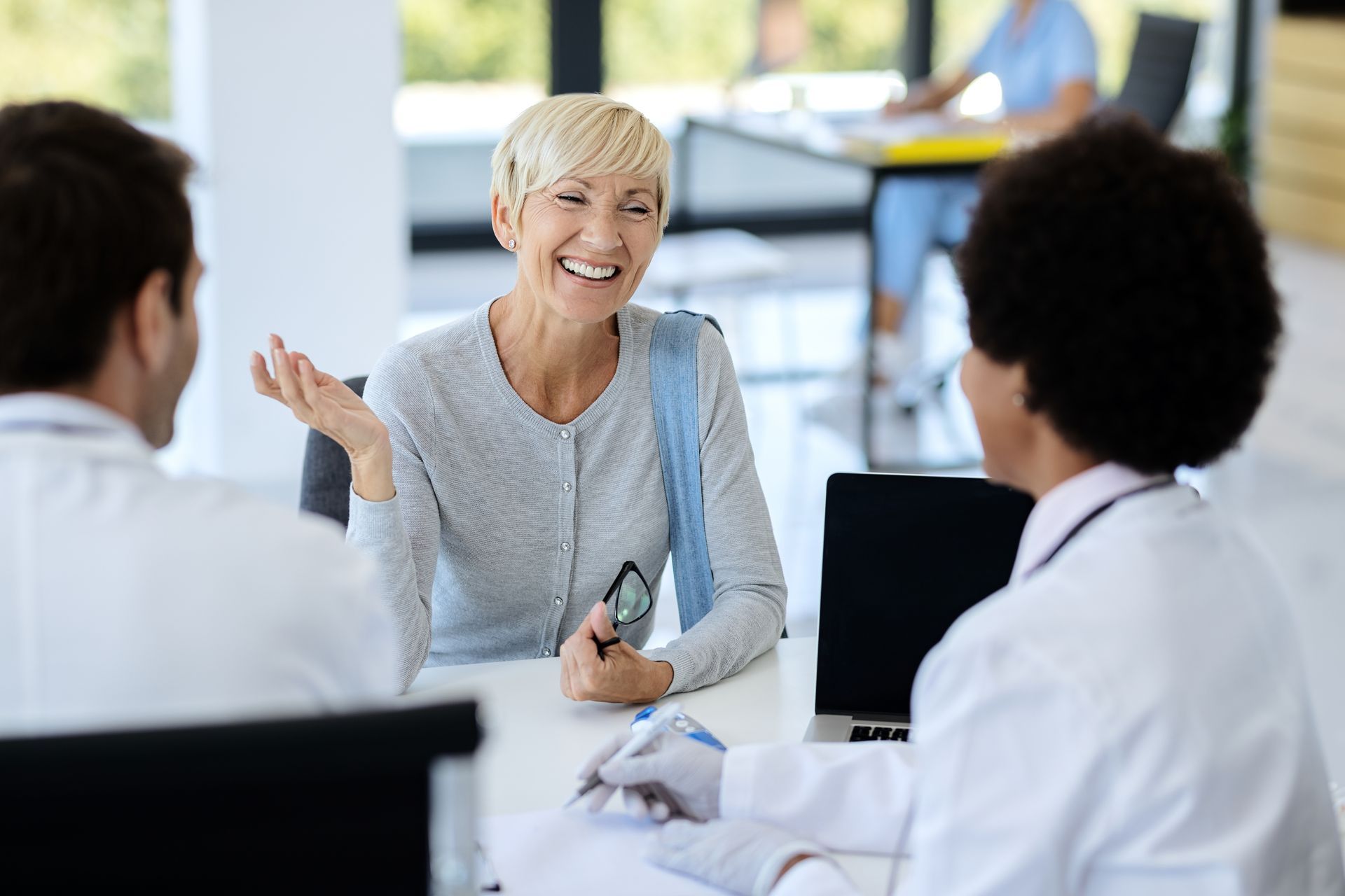 a woman is sitting at a table talking to two doctors .