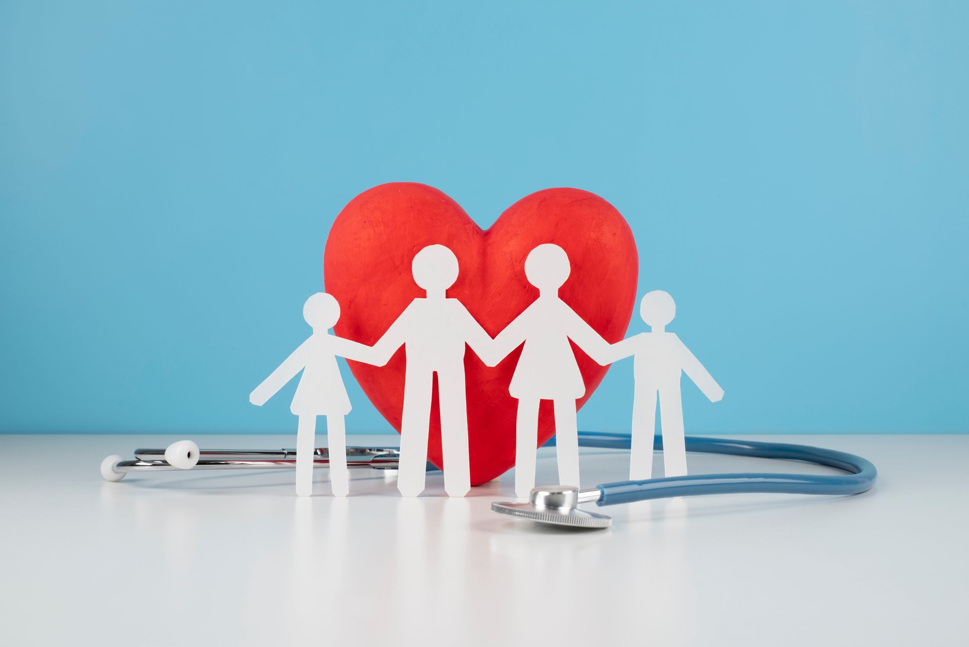 a paper family holding hands in front of a red heart and a stethoscope .