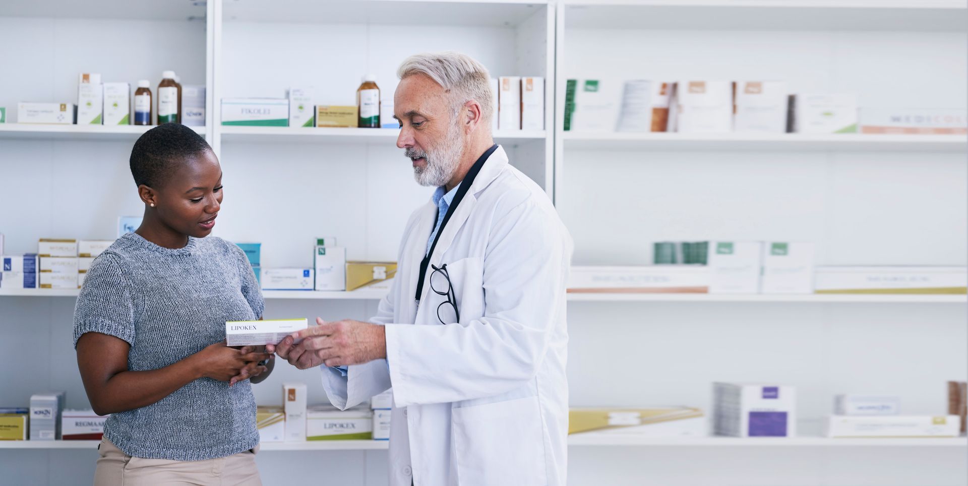 a doctor is giving a prescription to a patient in a pharmacy .