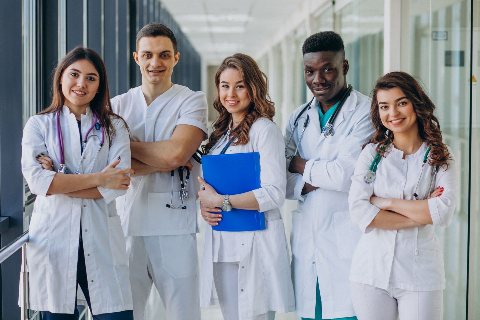 a group of doctors and nurses are posing for a picture in a hospital hallway .