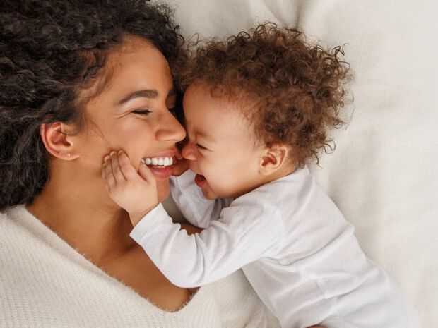 a woman and a baby are laying on a bed and looking at each other .