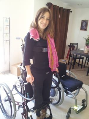 A woman is standing next to a wheelchair in a living room