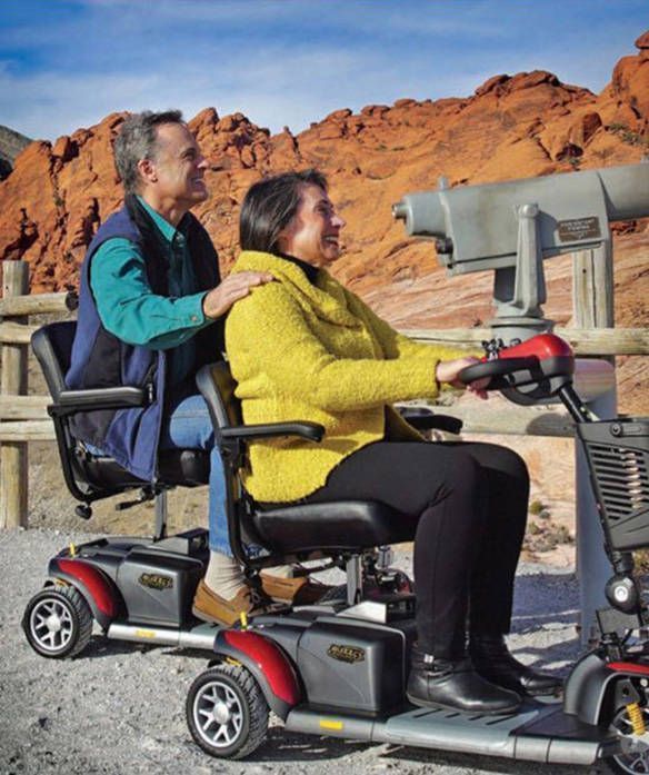 A man and a woman are riding a mobility scooter
