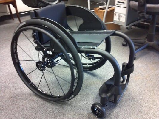 A black wheelchair is sitting on the floor in a room