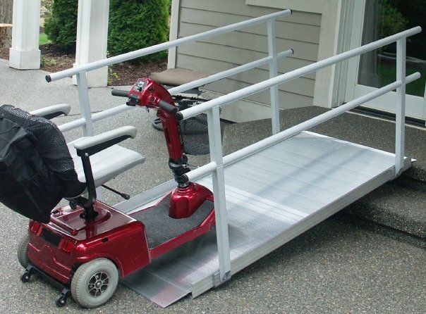 A red scooter is parked on a ramp in front of a house