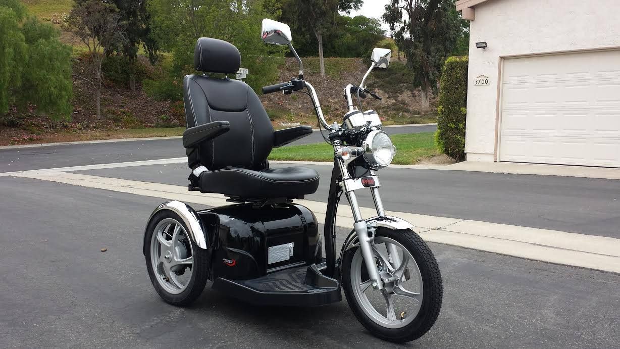 A scooter that looks like a motorcycle is parked on the side of the road.