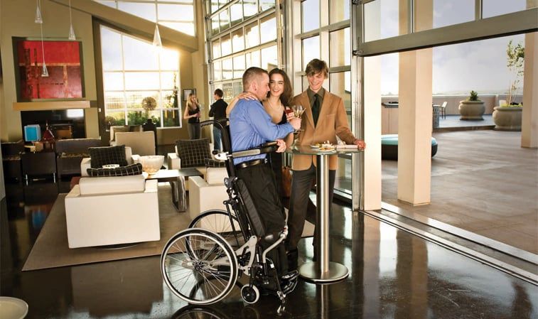 A man in a wheelchair is being pushed by two people