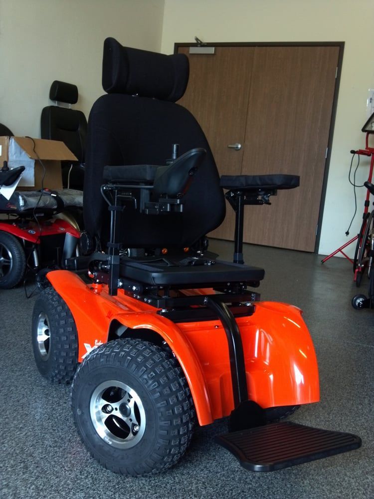 An orange wheelchair with a black seat sits in a room