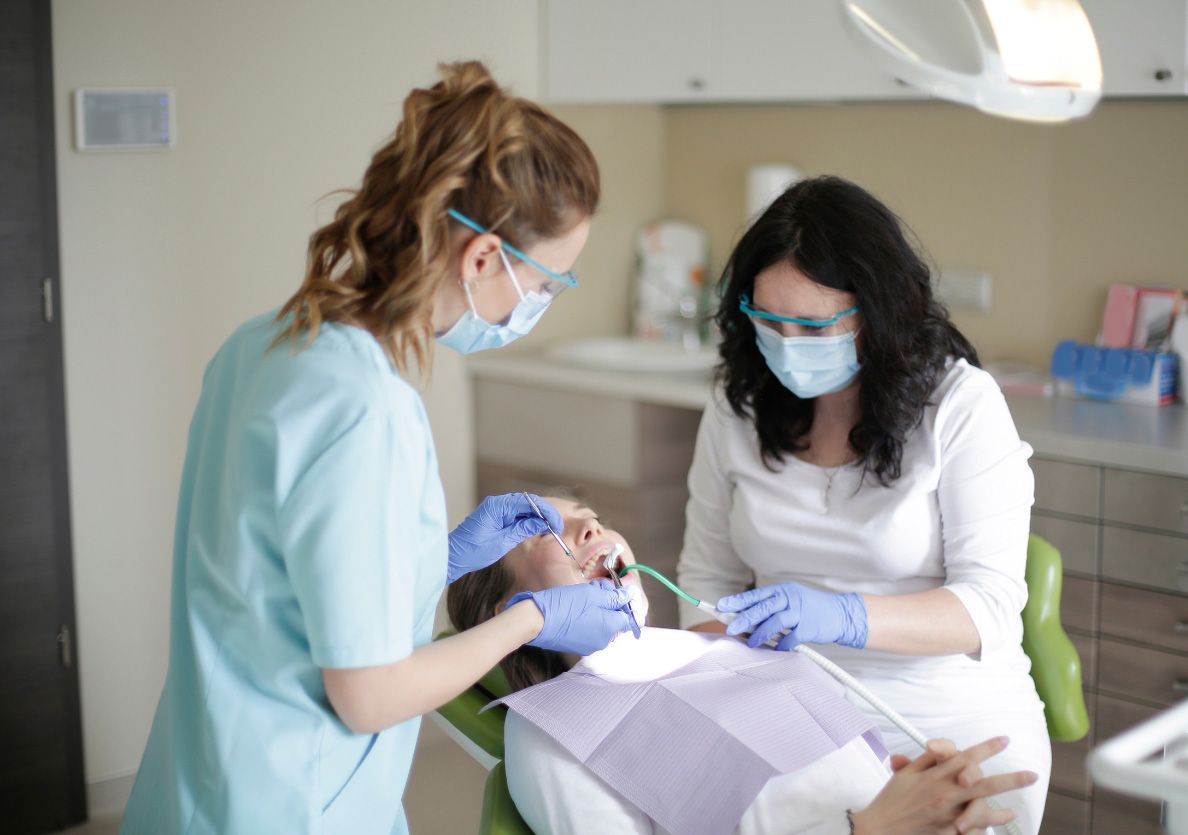 A dentist is examining a woman 's teeth in a dental office.