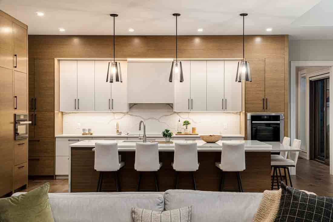 Modern kitchen with white cabinets, wood accents, island seating, and pendant lights