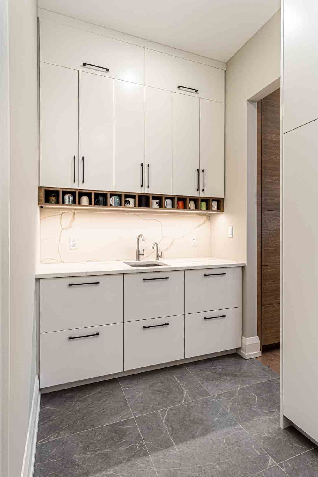 Small modern laundry room with white cabinets, sink, and dark tile floor
